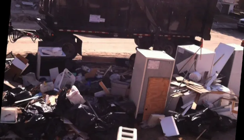 Ruined furniture and appliances piled at the curb beside a truck.