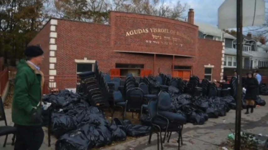 Stacked chairs and filled bags outside a brick shul after the flood.